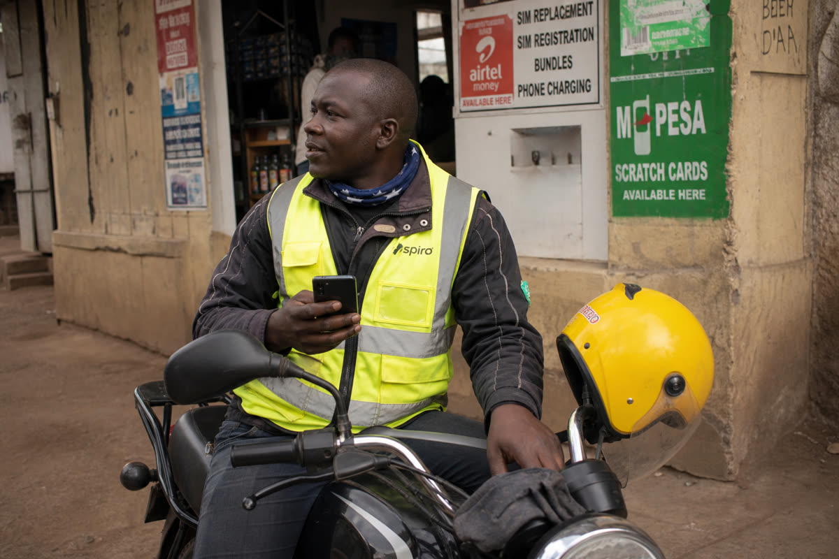 Rider with phone and motorcycle outside a shop