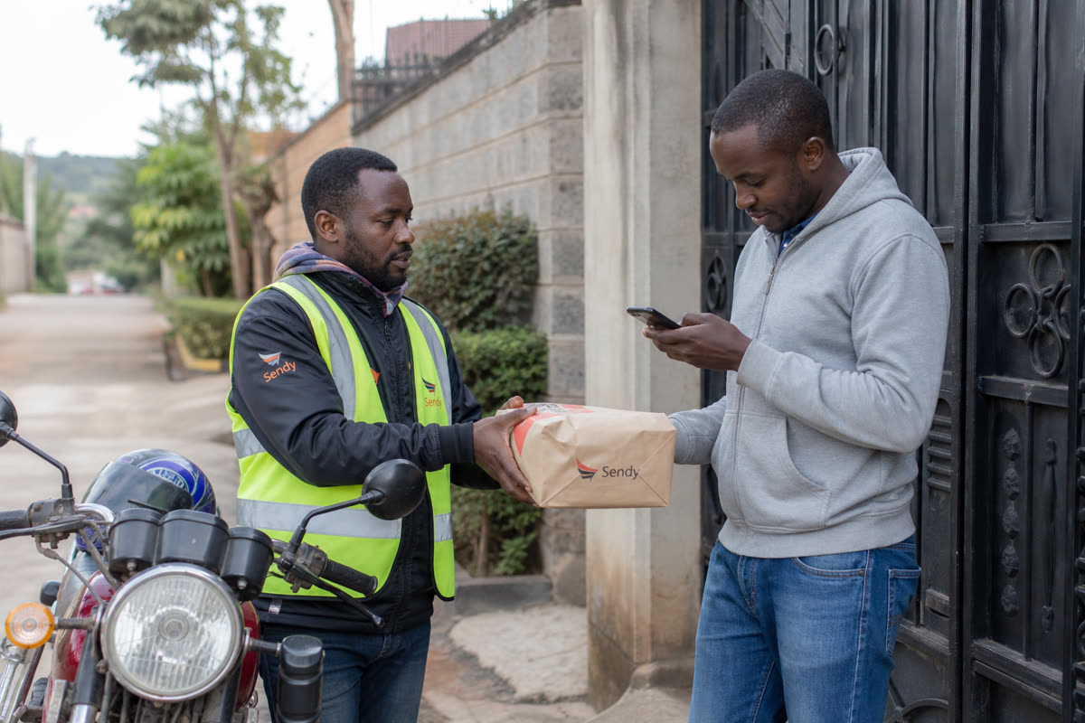 Rider handing a package to a buyer at a gate